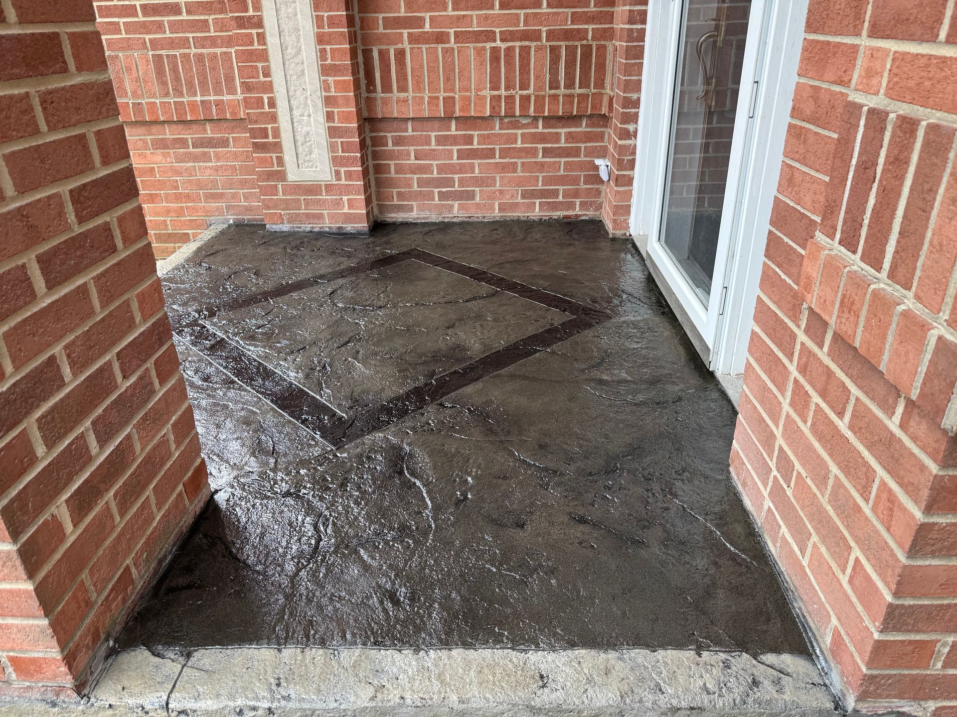 Brick entryway with wet, dark concrete floor. A diamond design is in the center.