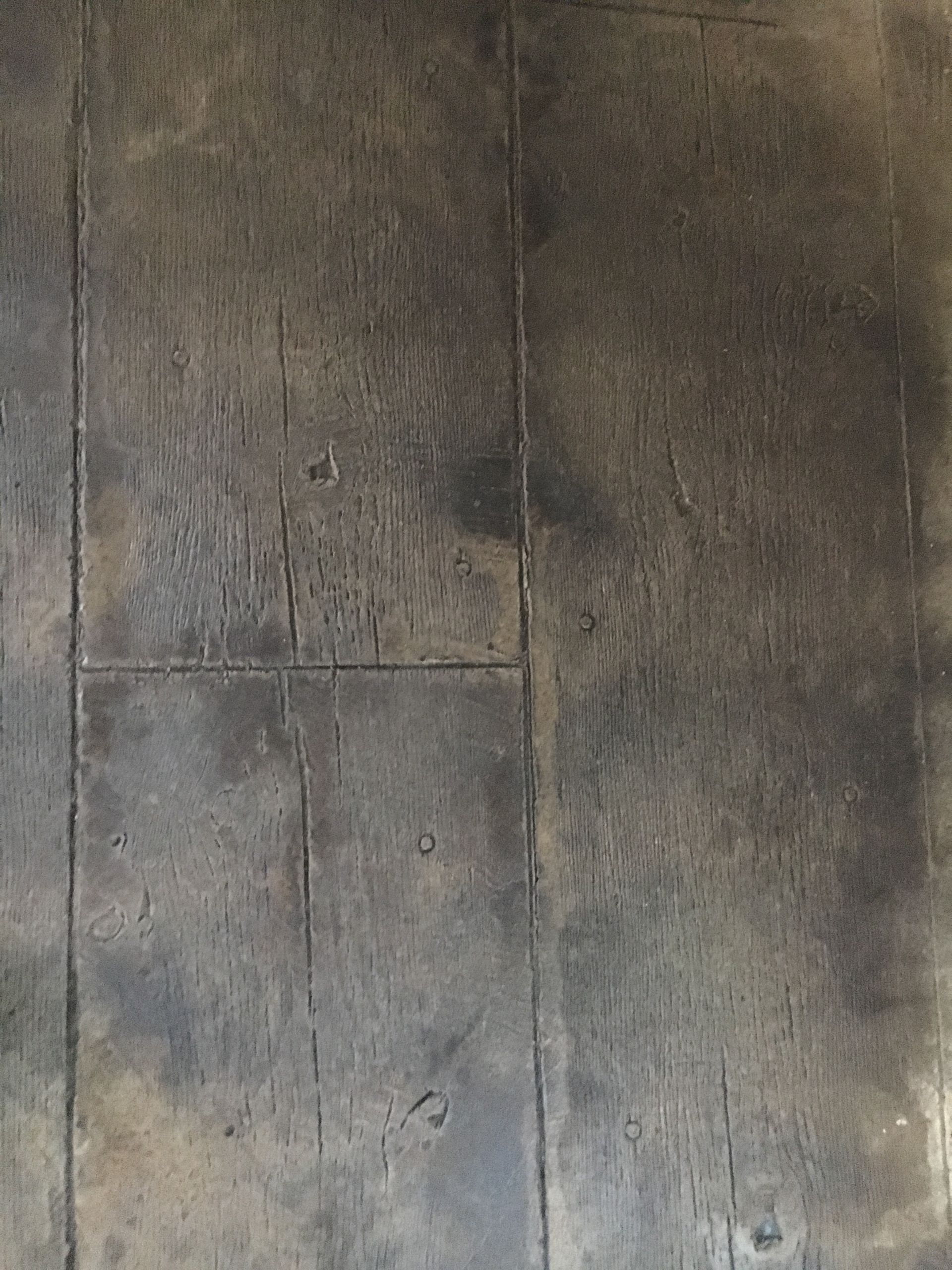 Dark wooden floorboards, showing the grain of the wood and wear and tear.