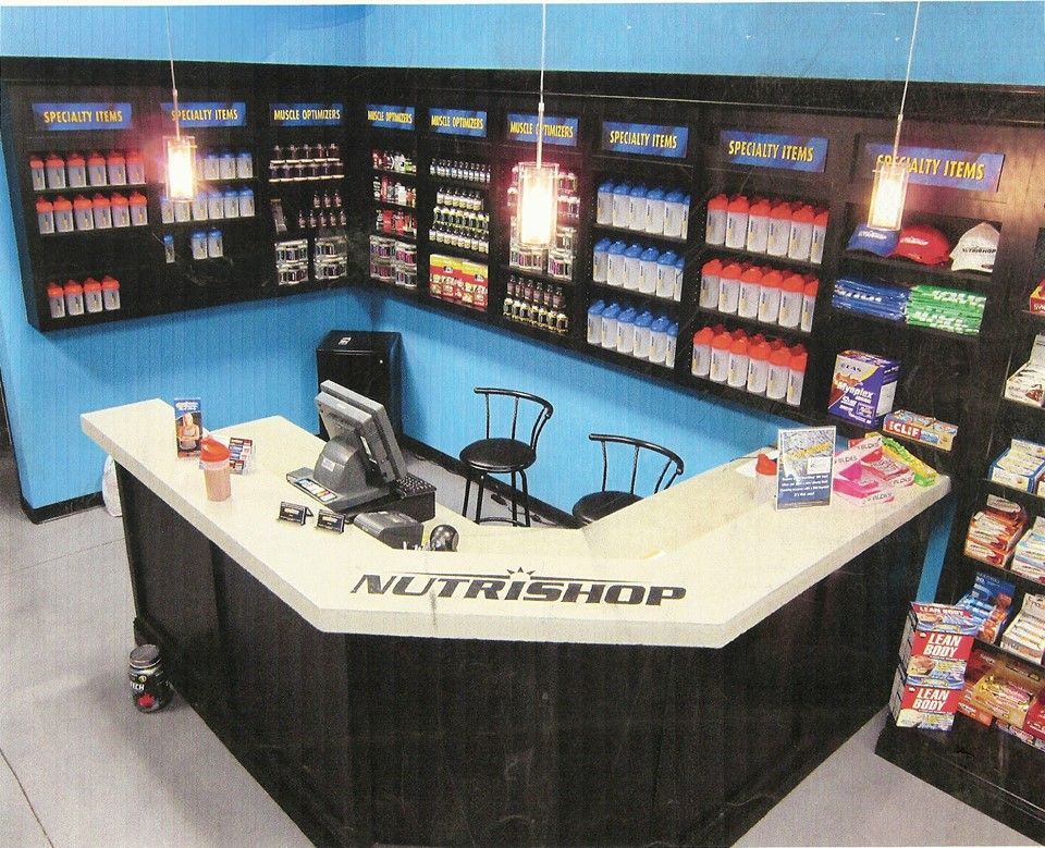 Inside a NutriShop store with supplements, counter, blue walls, and products on display.