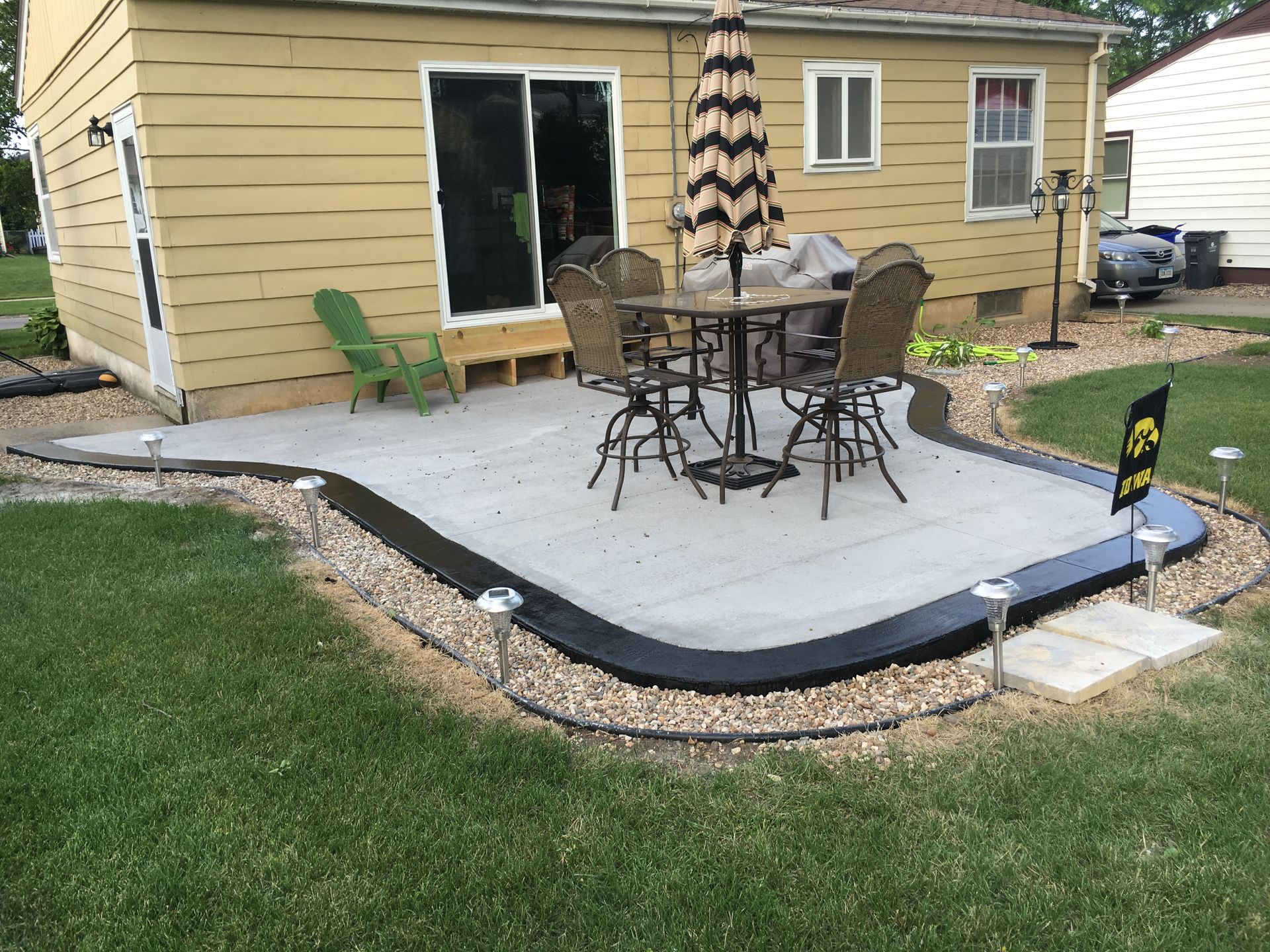 Backyard patio with table and chairs, surrounded by gravel and grass.