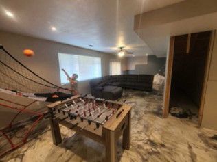 Person throwing a ball in a basement with a foosball table and sectional couch.