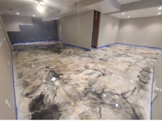 Finished basement with epoxy flooring in marble effect. Gray, black, and gold tones.