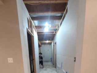 Hallway under construction with unfinished ceiling and a person in the distance.