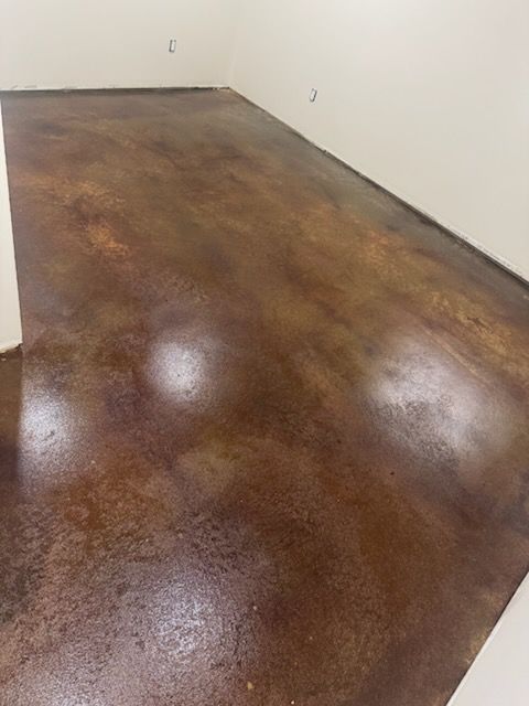 Brown stained concrete floor, reflective with hints of copper, in a room with white walls.
