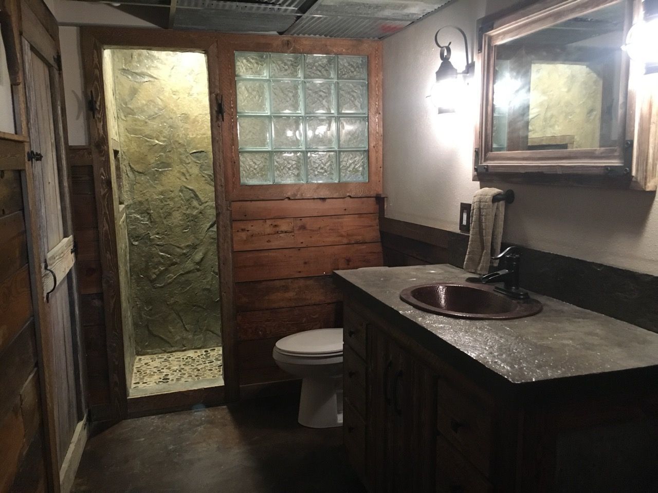 Rustic bathroom with wooden accents, including a shower, sink, and mirror.