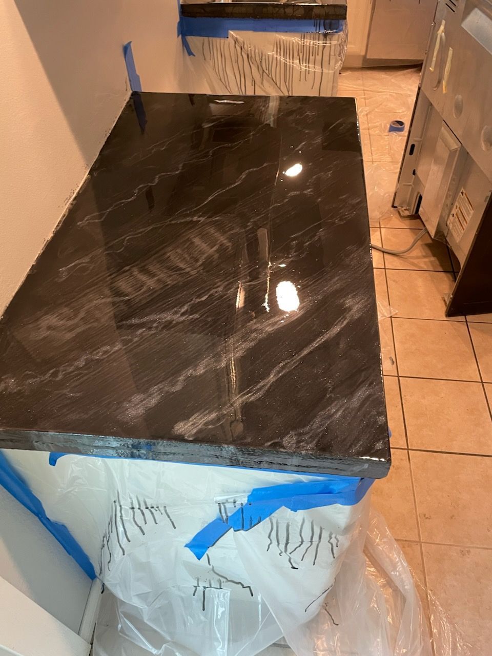 Black granite countertop installed on a white cabinet, taped with blue painter's tape.