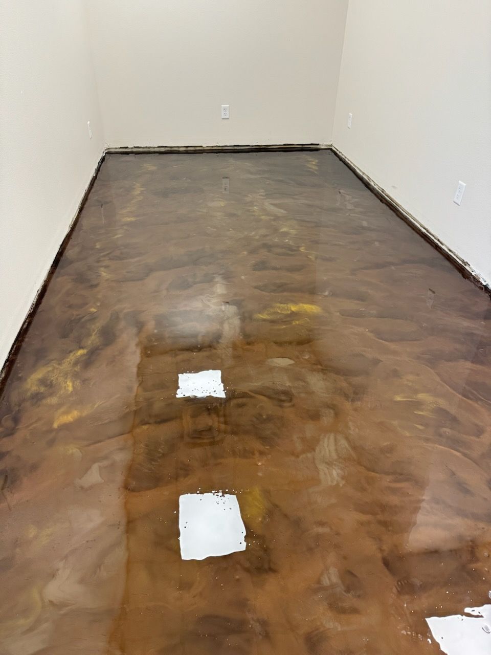 Metallic brown epoxy floor in a room with white walls, two square openings.
