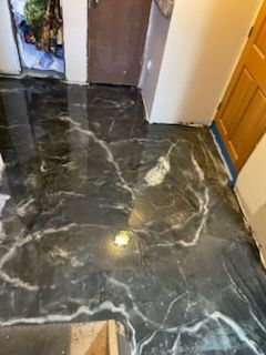 Black and white marbled flooring in a room with doorways, suggesting an interior space.