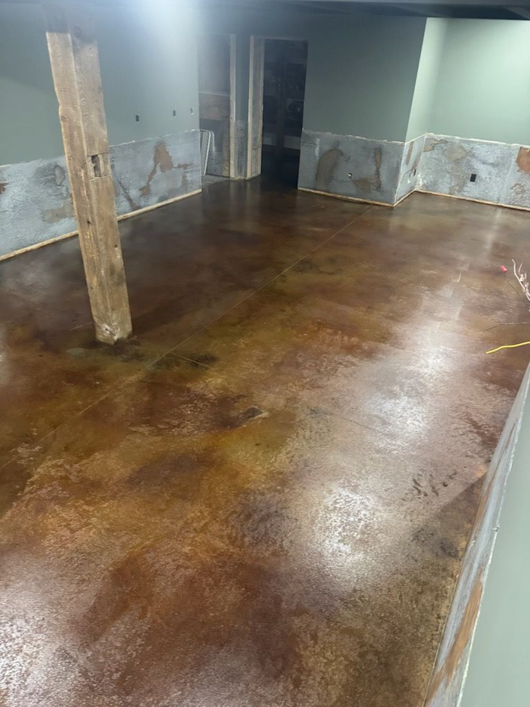 Brown stained concrete floor with a support beam and green walls.