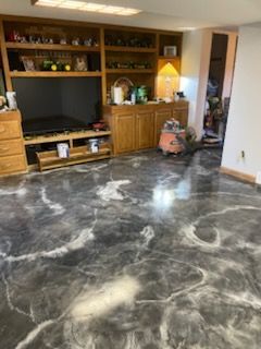 Grey marble epoxy floor in a room with wooden cabinets and a tv.