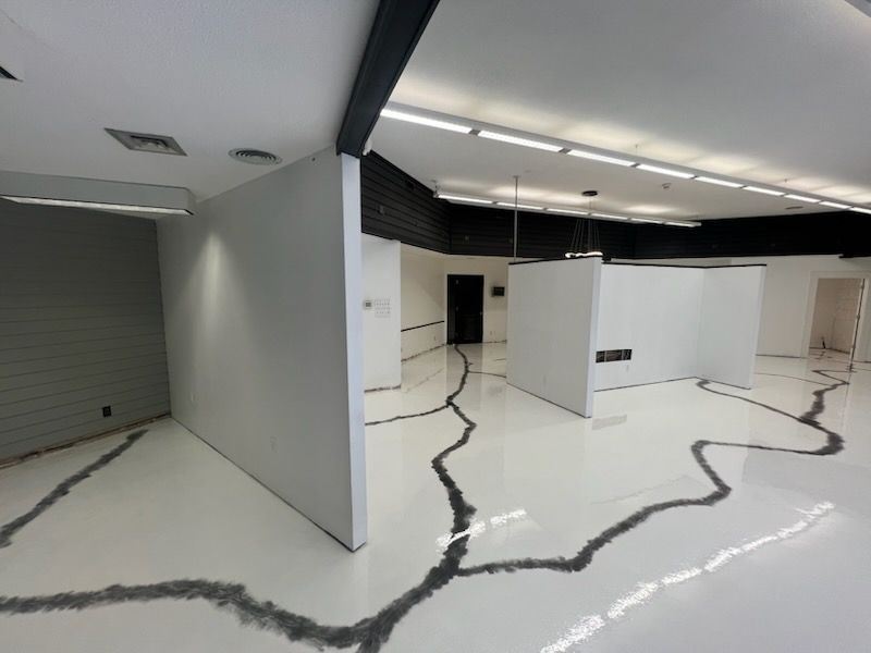 White gallery space with gray accents. Walls and floor have a black, cracked line design.