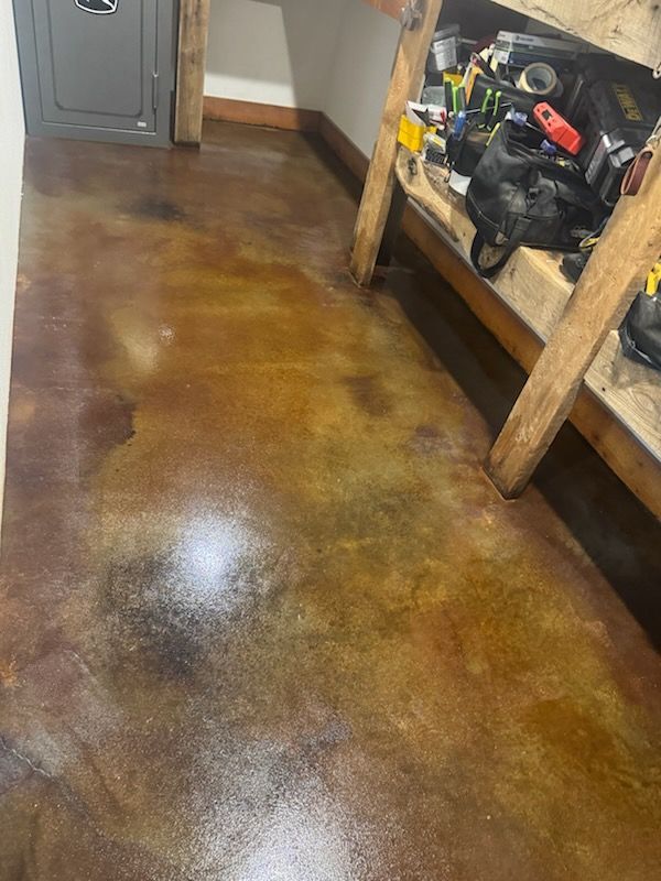 Concrete floor with brown and gold color variations, with a workbench and safe in the background.