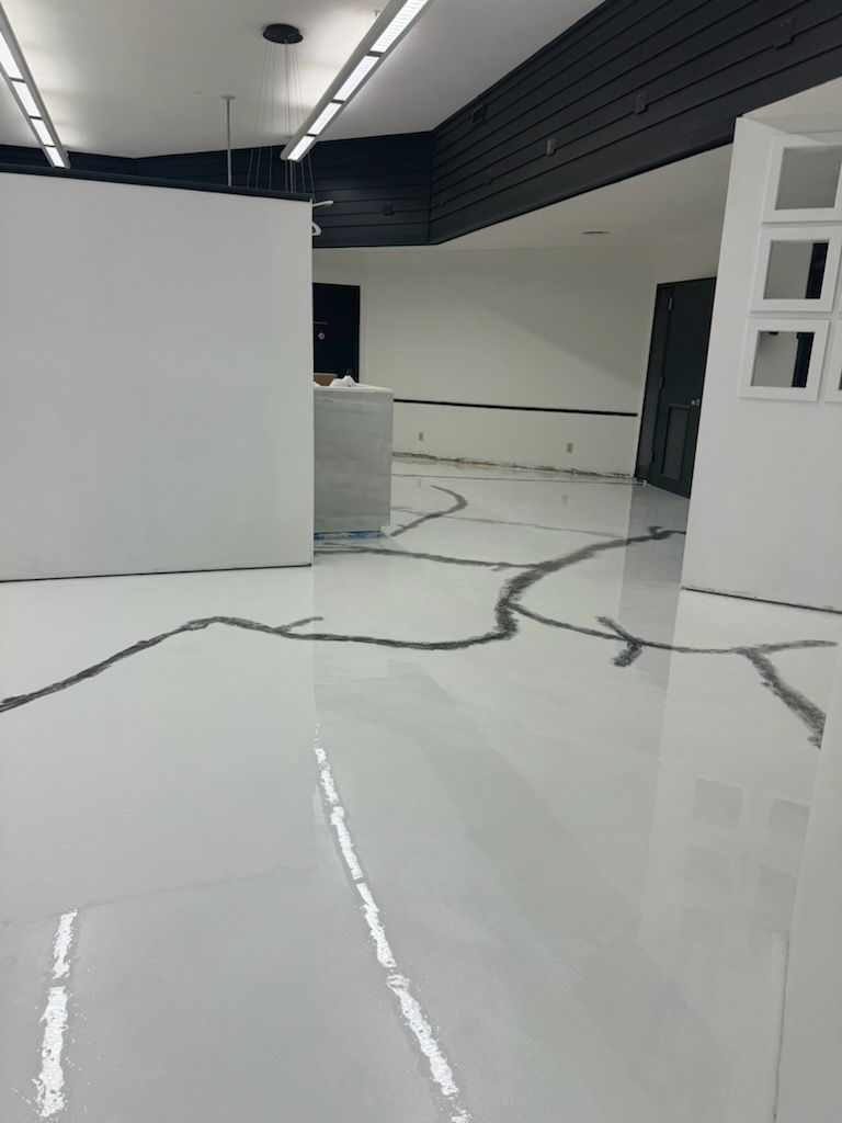 Empty retail space with white epoxy floor, black accents, and decorative dark gray lines.