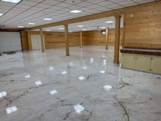 Spacious room with polished, marbled-effect floor, wooden beams and paneling, and neutral-colored cabinets.