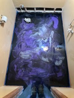 Purple and black epoxy floor with swirls in a bathroom.