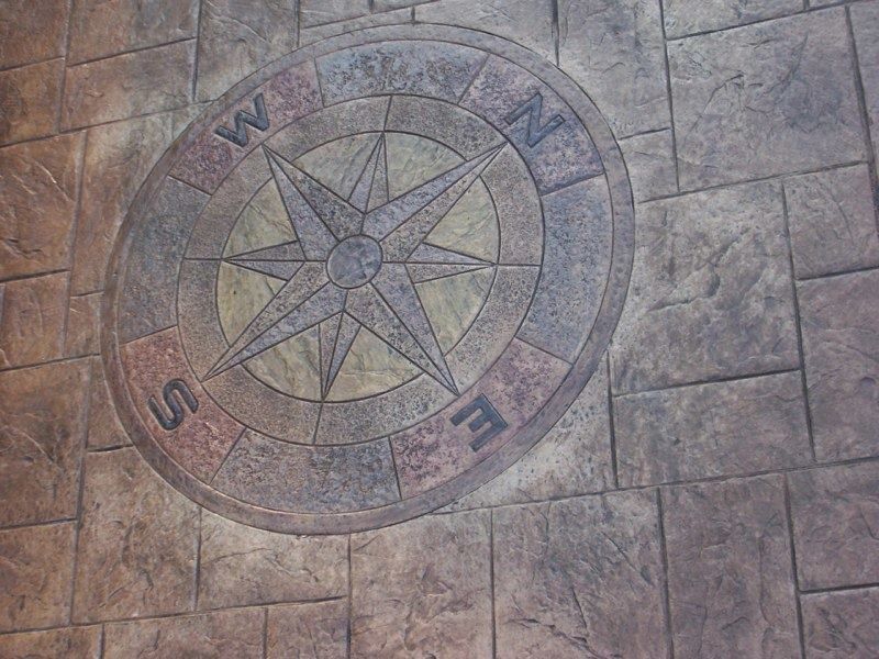 Compass design on textured concrete, with directional markers (N, S, E, W).