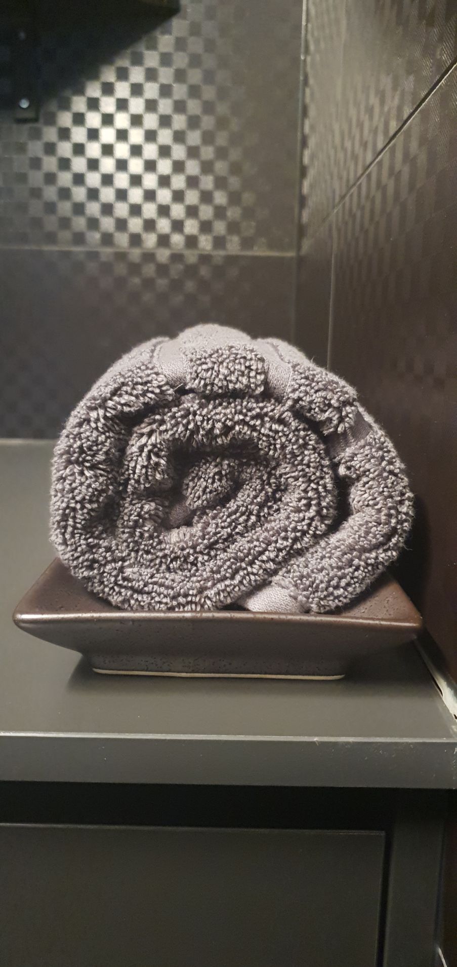 A towel is rolled up on a tray on a counter.