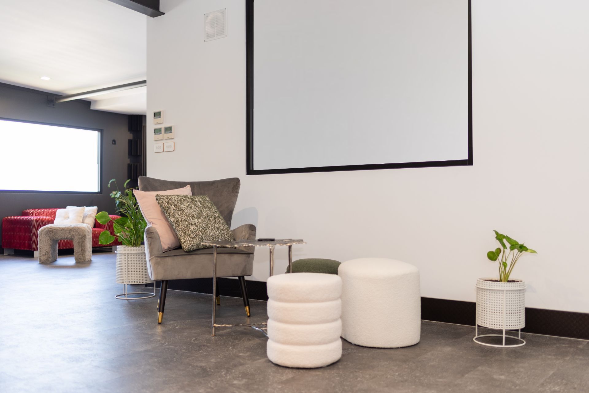 A living room with a chair , ottomans , and a projector screen.