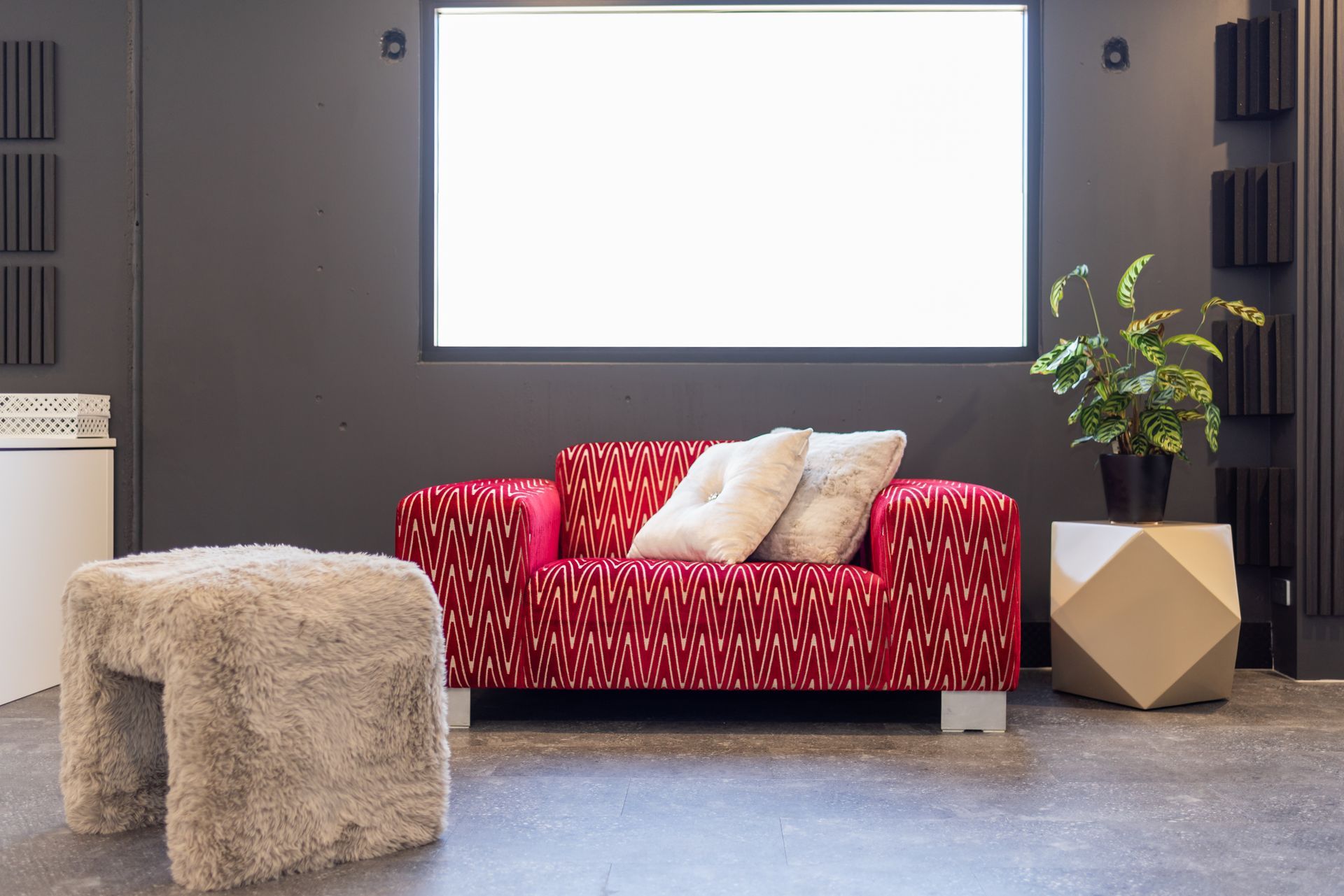A living room with a red couch and white pillows