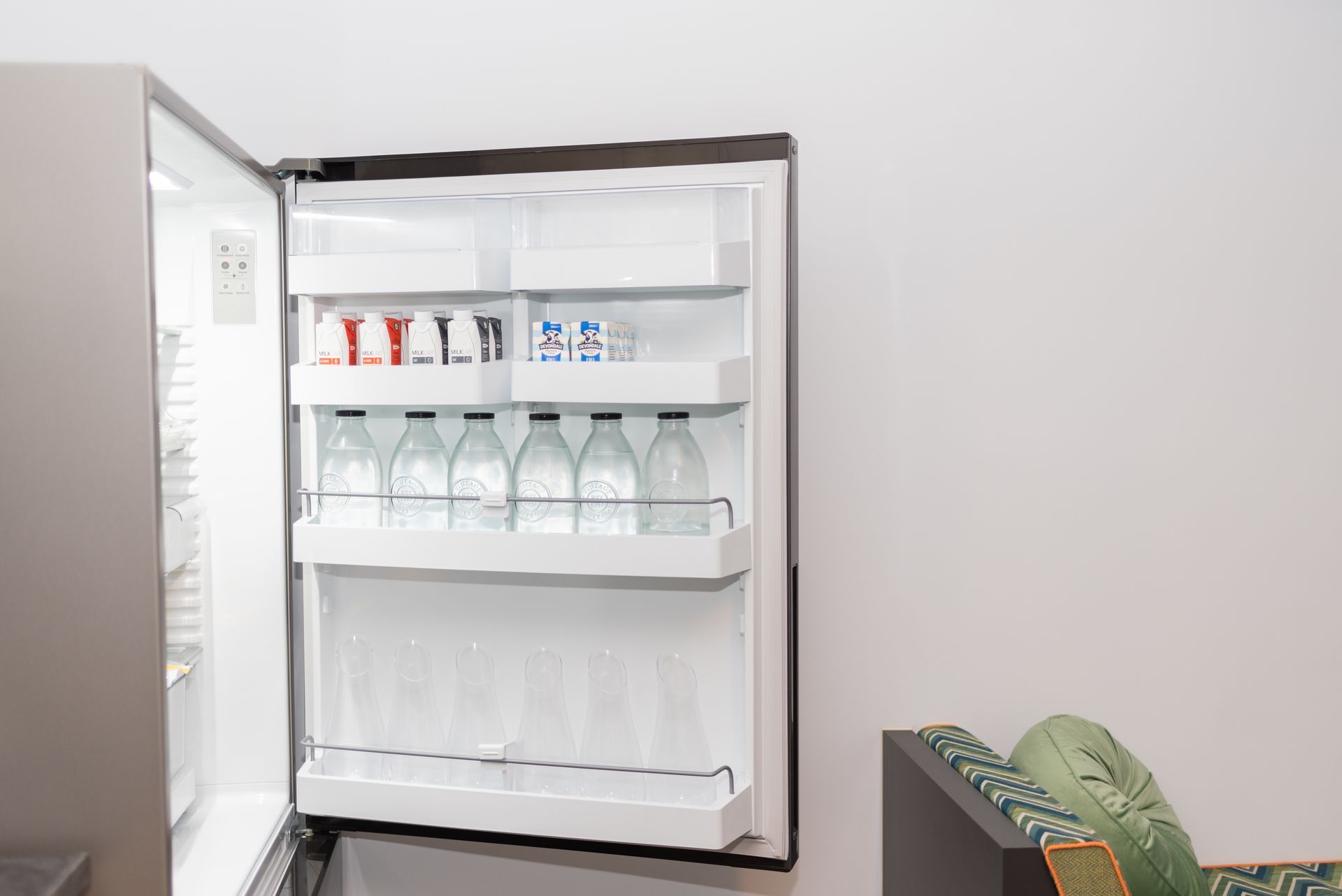 A refrigerator with the door open and bottles of water in it.