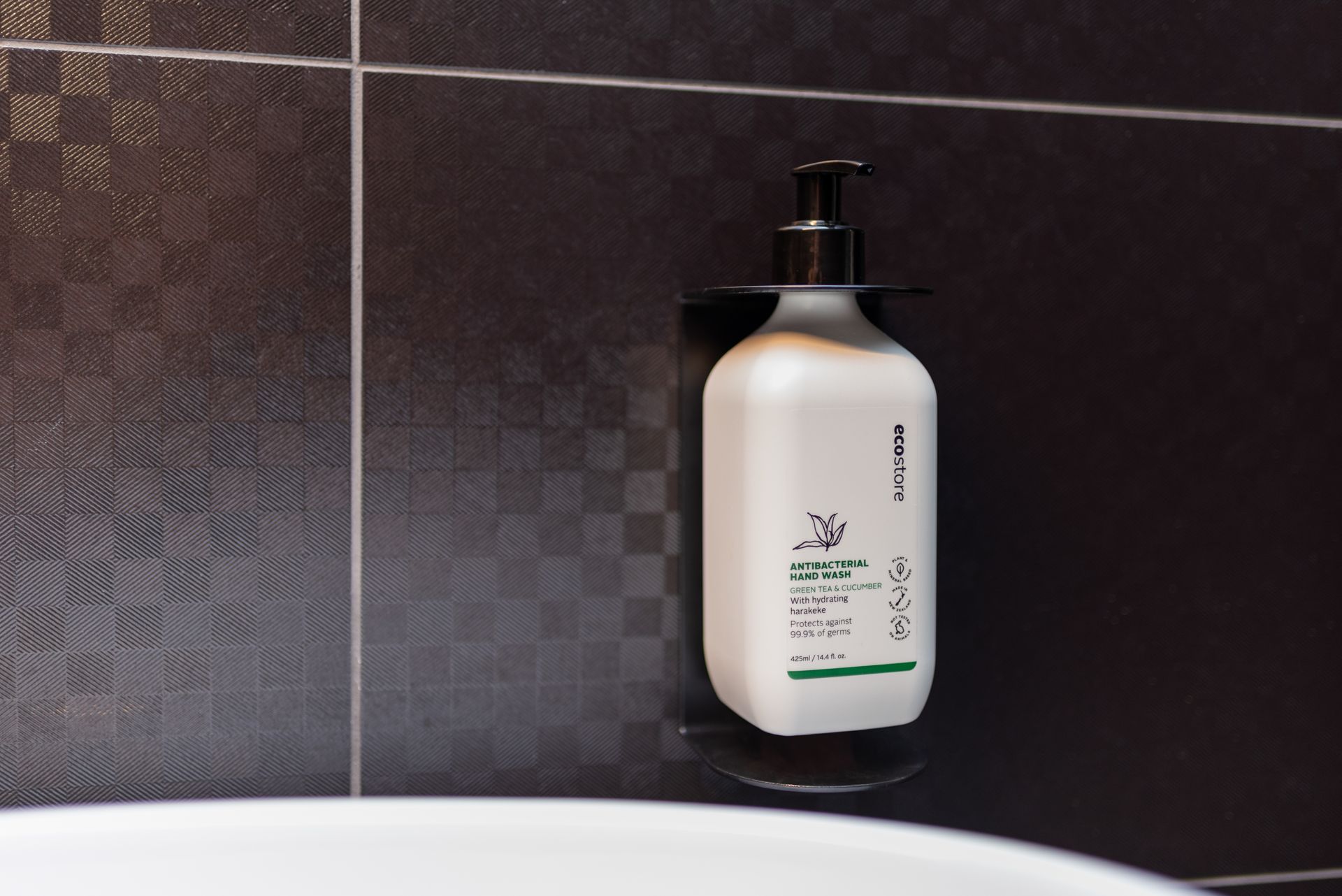 A bottle of lotion is hanging on a wall in a bathroom
