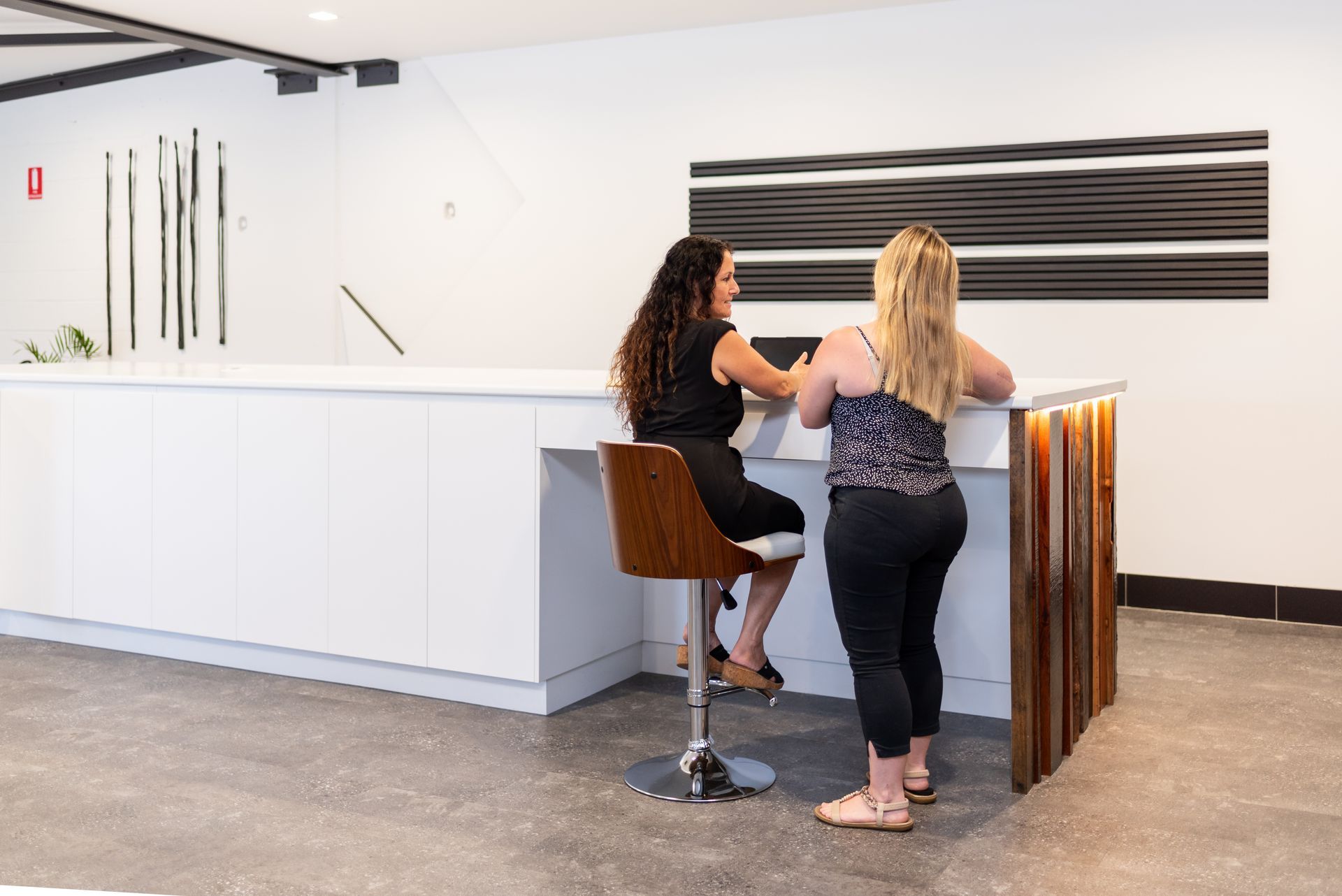 Two women are sitting at a bar talking to each other.
