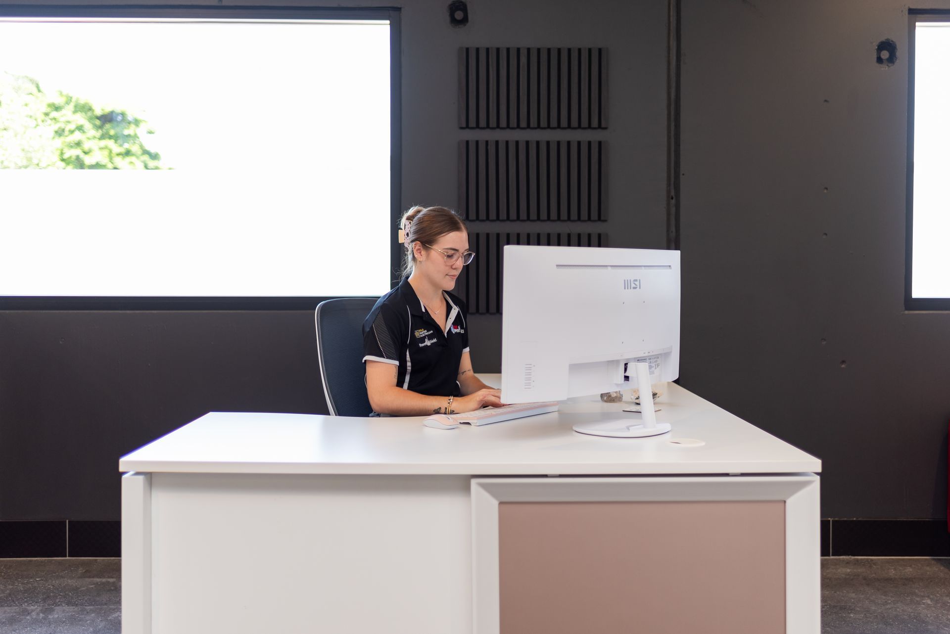 A woman is sitting at a desk in front of a computer.