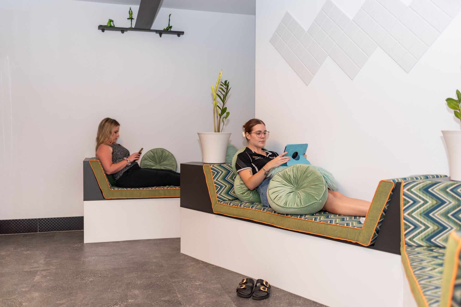 Two women are sitting on a couch looking at their phones.