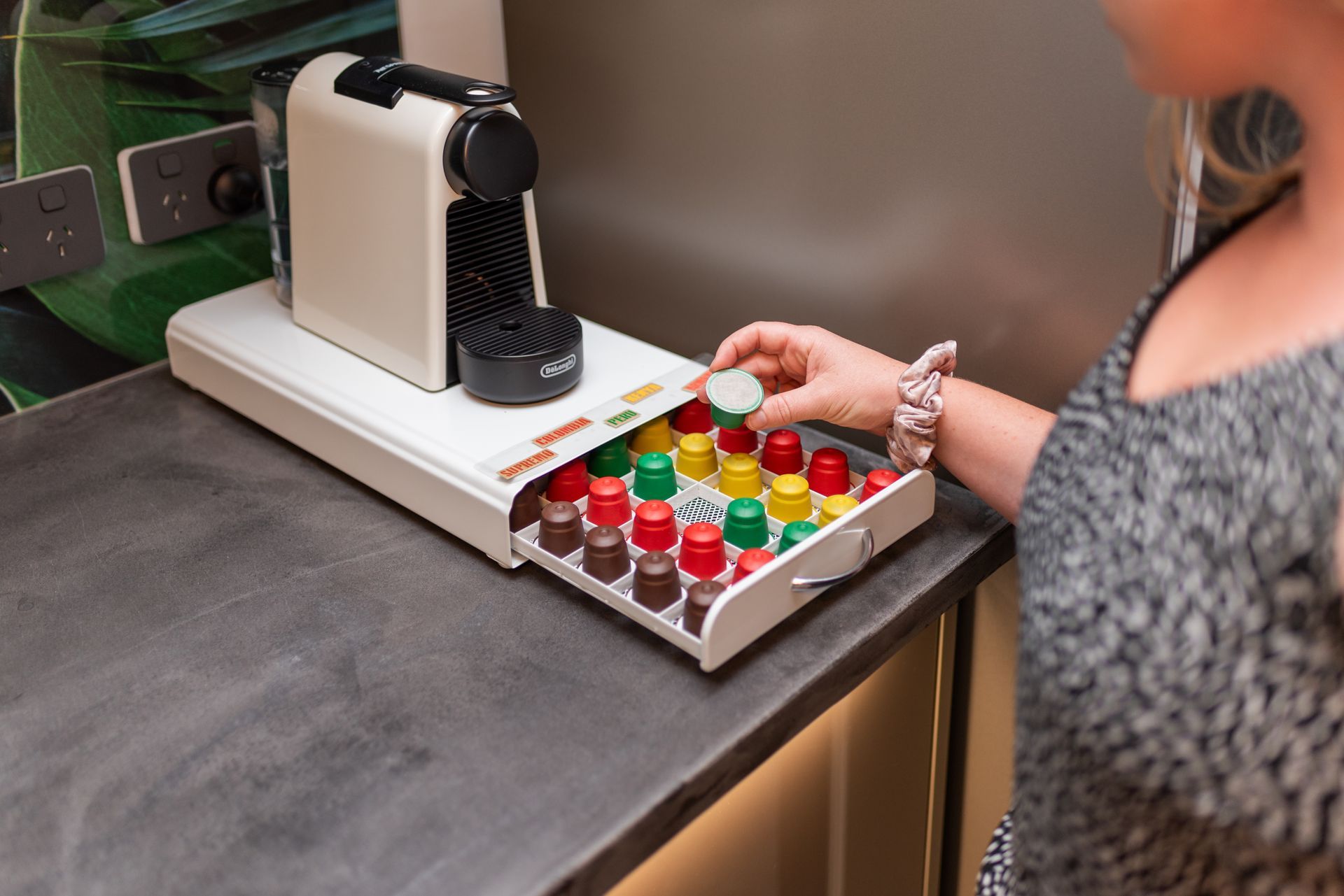 A woman is taking a capsule out of a nespresso machine.