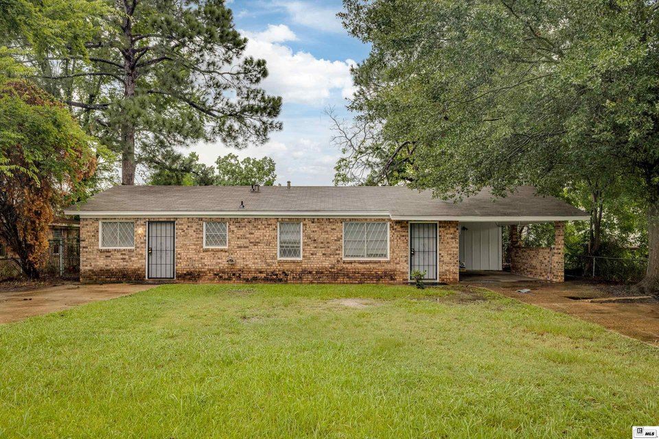 A brick house with a large lawn in front of it is for sale.
