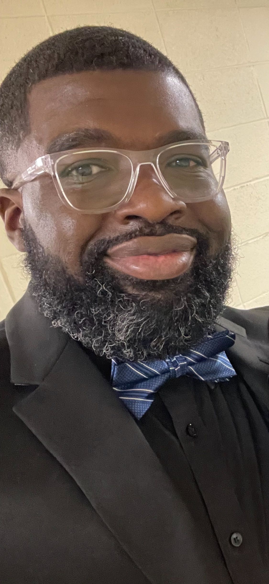 A man with a beard wearing glasses and a bow tie.