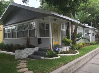A gray house with a yellow door and a porch.