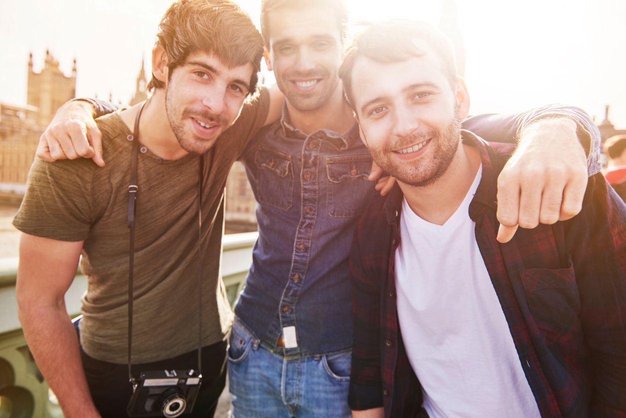 Three young men are posing for a picture together on a bridge.