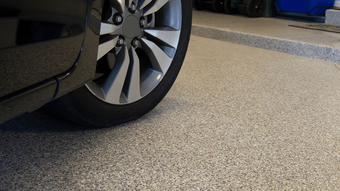 Car parked on a clean, speckled epoxy-coated garage floor with a polished look from an epoxy flooring service in Scottsdale, AZ