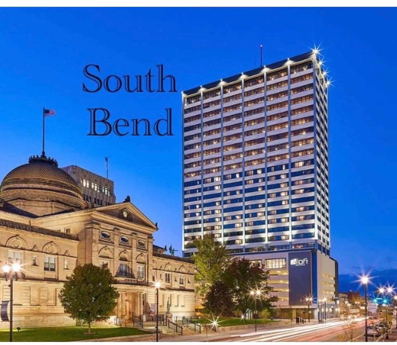 Black van parked on a paved road, possibly at an airport, with an airplane in the distance.