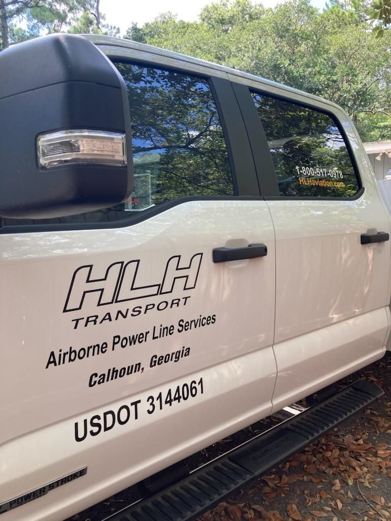 White HLH Transport van with company logo and USDOT number on the side, parked outdoors