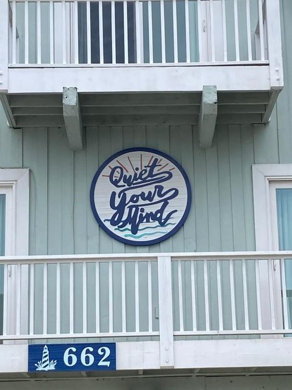 Blue apartment balcony with a round “Quiet Your Mind” sign and unit number 662