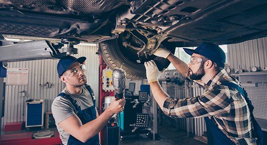 Two Men Working Under Car — Casselberry, FL — Casselberry Auto Service Two Men Working Under Car — Casselberry, FL — Casselberry Auto Service