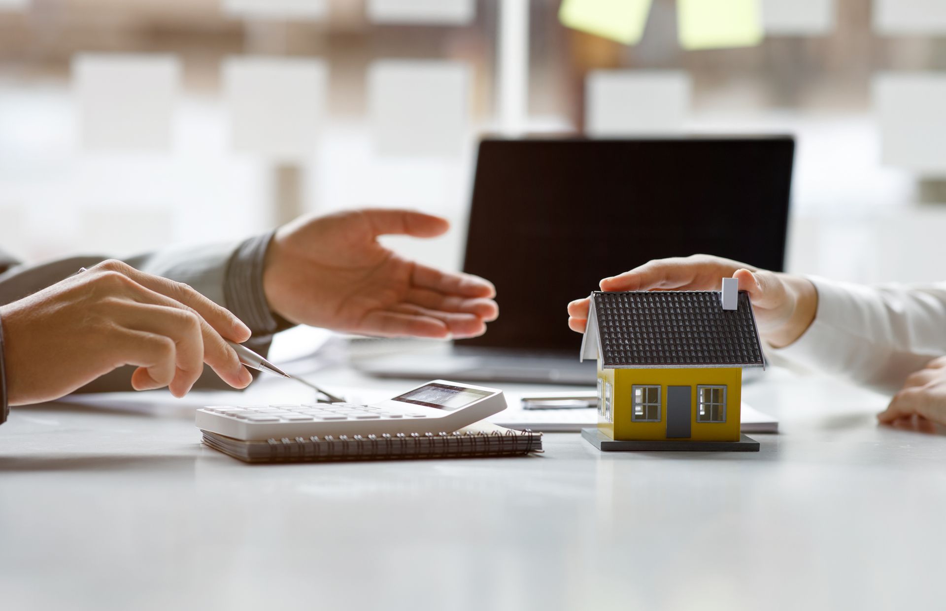 A man and a woman are sitting at a table holding a model house.