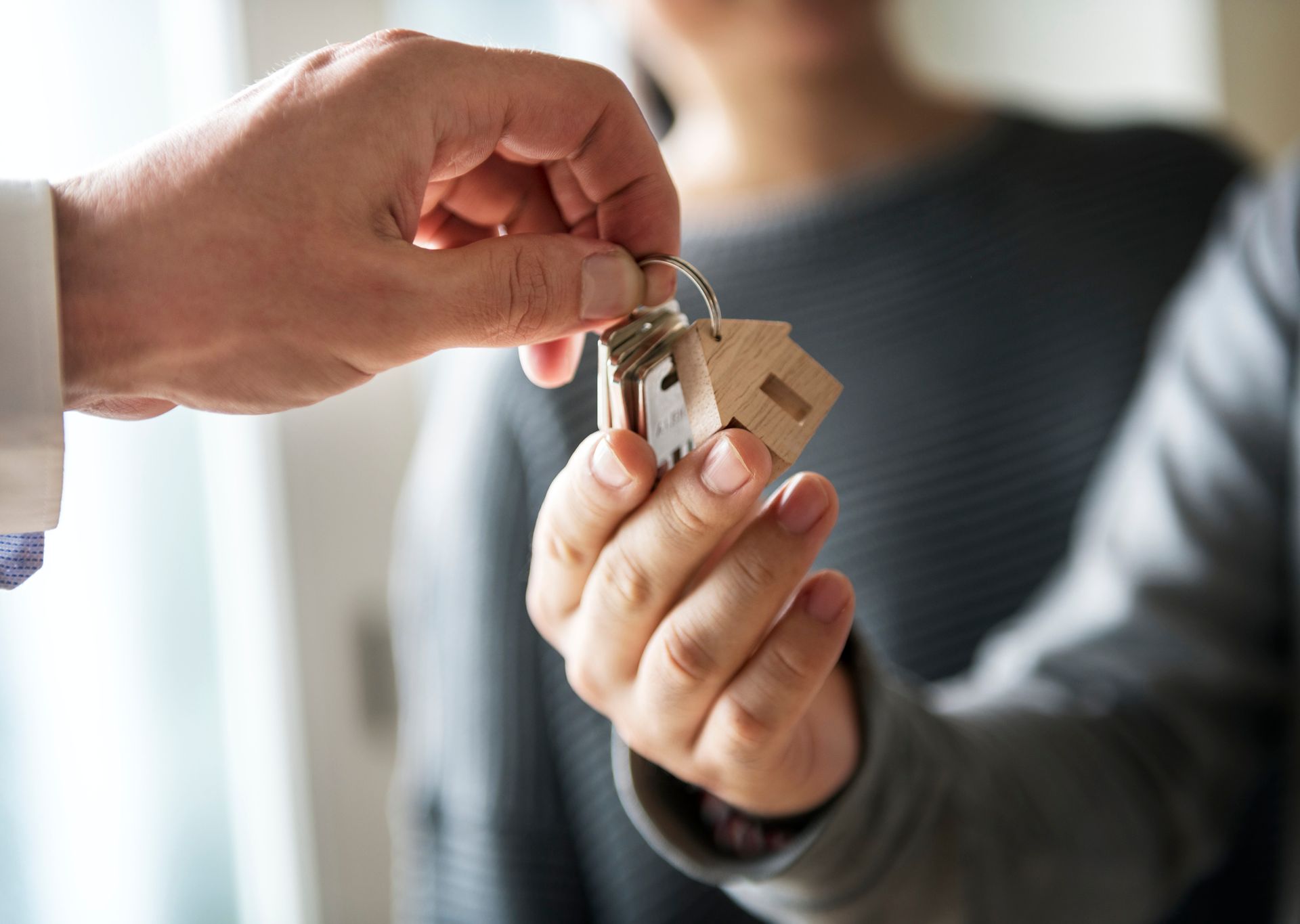 A man is handing a woman a set of house keys.