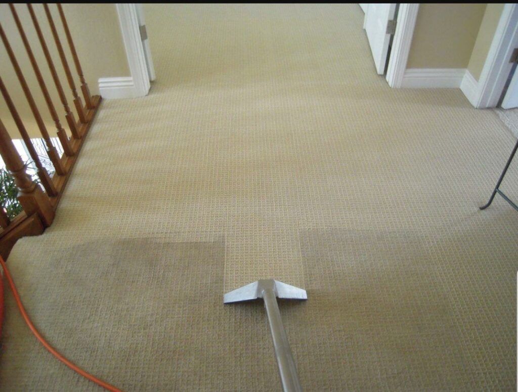 Carpet being cleaned with a professional cleaning machine on a beige carpeted hallway.