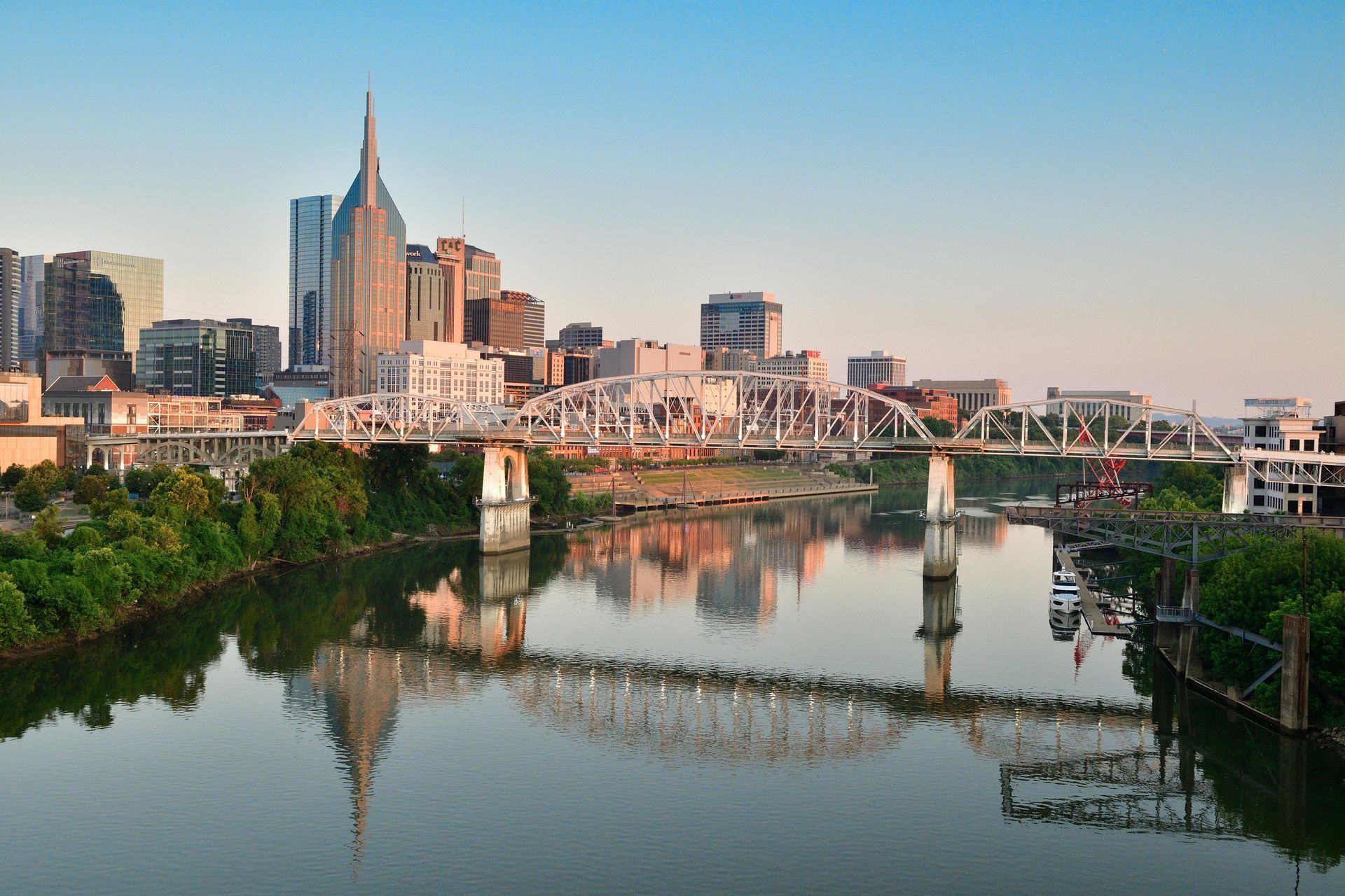 Nashville skyline with bridge reflecting in the river at sunset.