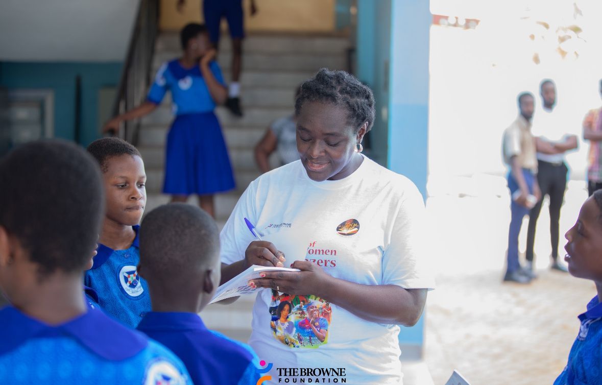 Woman signing items for a group of school children outdoors.
