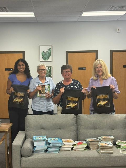 Four women holding books and tote bags that say 