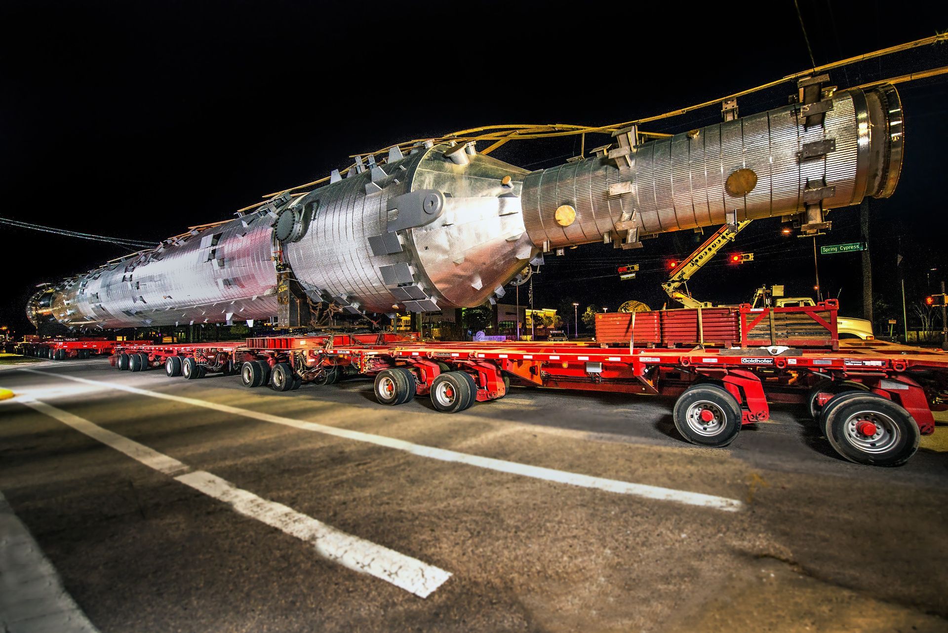 A large spacecraft component is transported on a multi-axle truck at night.