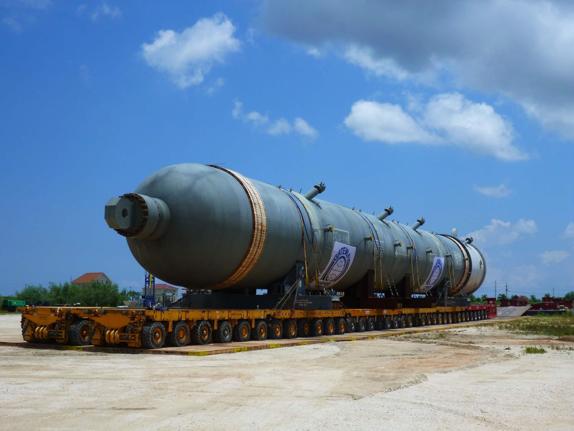 Large, cylindrical industrial vessel on a trailer, outdoors under a blue sky.