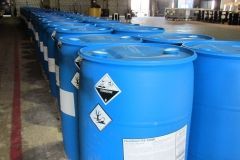 Blue chemical storage barrels with hazard labels in a warehouse.