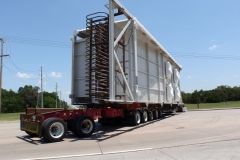 Large white industrial structure on a flatbed truck, parked on the side of a road.