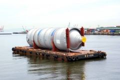 Large cylindrical tank on a barge in water, likely at a port.