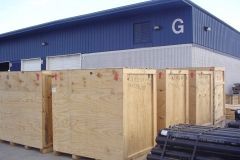 Wooden crates in front of a blue and white warehouse building. 